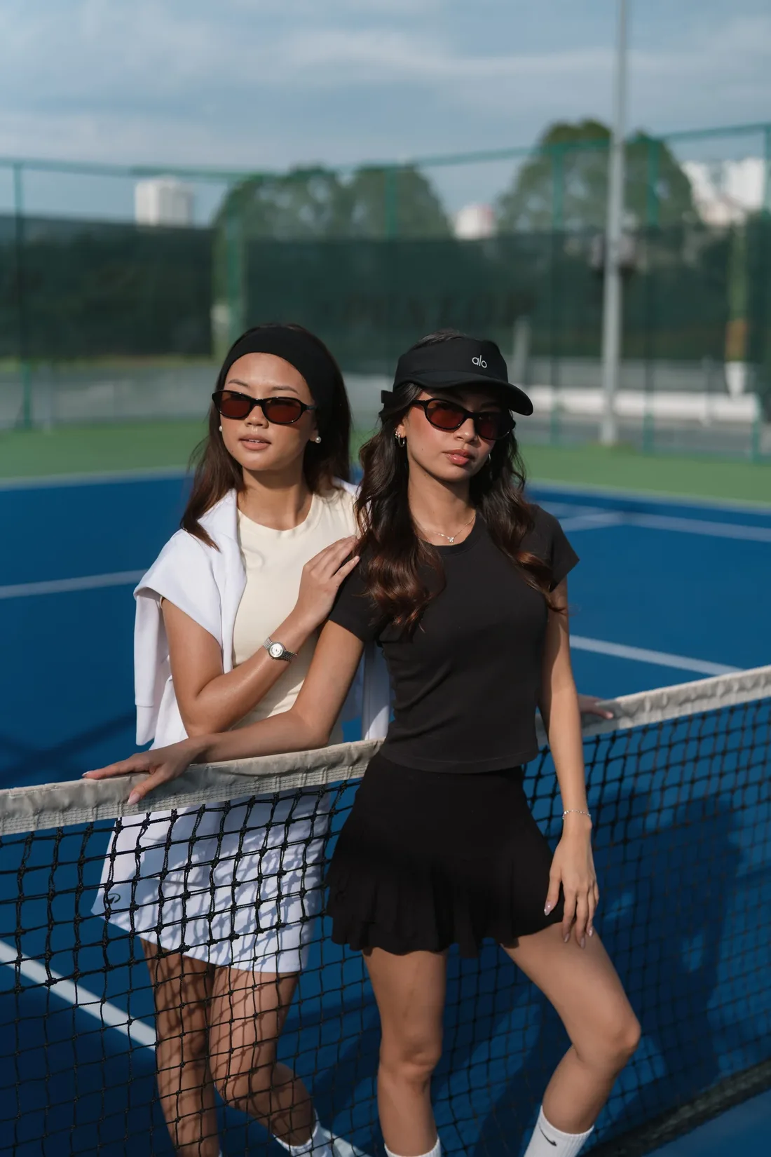 Two women at a tennis net wearing Neloire Como